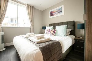 a bedroom with a large bed with towels on it at Urban Living's - The Wren Beautiful City Centre Apartment with Parking in Oxford