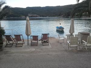 a group of chairs and umbrellas and a boat in the water at Villa Kukuljica in Zaton