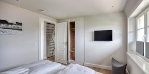 1 dormitorio con 1 cama y TV en la pared en Rantum Dorf - Ferienappartments im Reetdachhaus 3 & 4, en Rantum