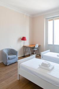 een witte kamer met 2 bedden en een bureau bij Comfy Apartment Near Fortezza Da Basso in Florence