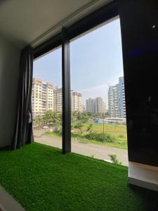 a room with a window with green grass and buildings at HOTEL CROWN PALACE in Surat