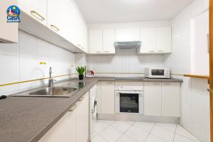 cocina blanca con fregadero y microondas en Apartamentos Nova Romana Casa Azahar, en Alcossebre