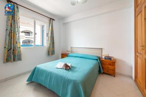 a bedroom with a bed with a blue blanket at Apartamentos Nova Romana Casa Azahar in Alcossebre