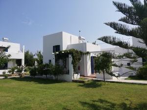 Blick auf ein weißes Haus mit einem grünen Hof in der Unterkunft Liostasi Houses in Skyros