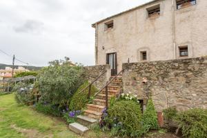 - un bâtiment en pierre avec des escaliers à côté d'un mur en pierre dans l'établissement Turismo Rural Can Massot, à Darnius