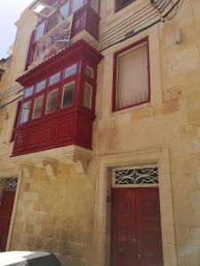 un edificio con puertas rojas y ventanas. en Two gate town house, en Senglea