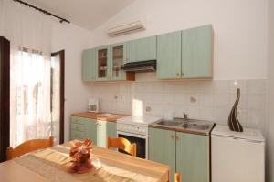 a kitchen with green cabinets and a table and a sink at Apartments with a parking space Liznjan, Medulin - 7214 in Ližnjan