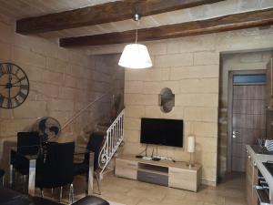 uma sala de estar com televisão numa parede de tijolos em Two gate town house em Senglea