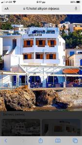 a large white building on a cliff near the water at Hotel Alkyon in Khóra Sfakíon