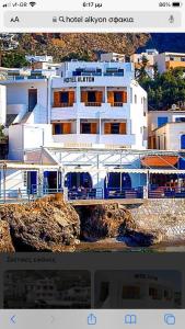 a large white building on a cliff near the water at Hotel Alkyon in Hora Sfakion