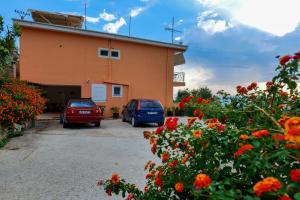 zwei Autos, die vor einem Gebäude mit Blumen geparkt sind in der Unterkunft Villa Ani in Borsh