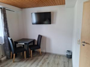 a room with a table and chairs and a tv on the wall at Zum Goldenen Fass in Nassau