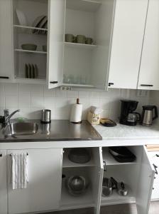 una cocina con armarios blancos y fregadero en Ihan Puotilan Metron lähellä en Helsinki