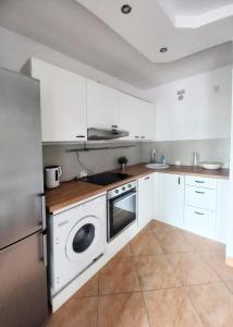 a kitchen with white cabinets and a washer at Warsaw Concierge Franciszkańska Old Town in Warsaw