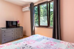 a bedroom with a bed and a tv and a window at Bendida Park in Velingrad