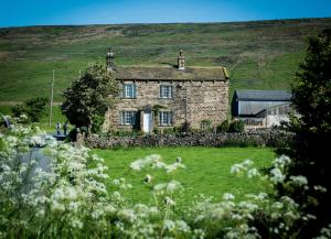 uma velha casa de pedra no meio de um campo em Crown Cottage Farm em Skipton