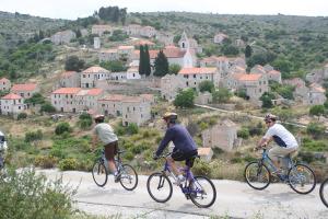 Tres hombres en bicicleta por un camino delante de un pueblo en Traditional gulet, cruises & events, en Split
