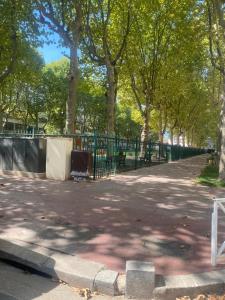 ein Park mit einem Zaun und Bäumen und einem Gehweg in der Unterkunft Charmant 2 pièce 35m2 in Montrouge