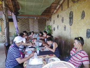 a group of people sitting at a table eating food at Why not restobar cottages in Sabang
