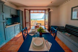 a dining room with a blue table and a kitchen at Villaggio Cala Mancina in San Vito lo Capo