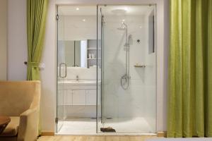 a glass shower in a bathroom with a sink at Super OYO Capital O 1169 Le Grand Hanoi Hotel - The Charm in Hanoi