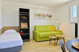 a bedroom with a bed and a green couch at Résidence Easy Lodge in Ajaccio