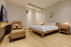 a bedroom with a bed and a tv and a chair at Super OYO Capital O 1169 Le Grand Hanoi Hotel - The Charm in Hanoi