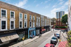 a city street with cars parked in front of buildings at Lady on the Lane- 2 bed Primrose Hill in London