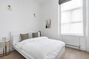 a white bedroom with a white bed and a window at Lady on the Lane- 2 bed Primrose Hill in London