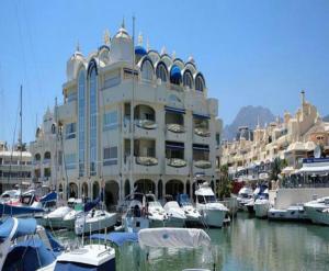 a large building with boats docked in a marina at Sea and mountain view Room with pool- Habitación PISO COMPARTIDO para 1 persona in Benalmádena