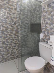 a bathroom with a toilet and a glass shower at Casinha do Cadu in Fernando de Noronha