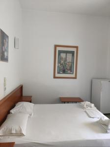 a bedroom with a large bed with white sheets at Hotel Ritsa in Kamena Vourla