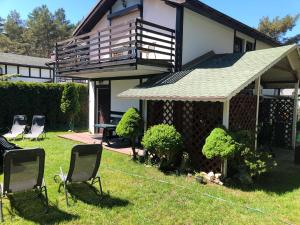 a house with a deck and chairs in the yard at Dom letniskowy Dorota in Poddąbie