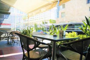 einen Tisch und Stühle auf einer Terrasse mit einem Auto auf einem Parkplatz in der Unterkunft Beverly Hotel Beirut in Beirut