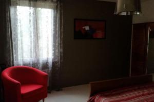 1 dormitorio con silla roja y ventana en Mas catalan avec piscine privative, en Camélas