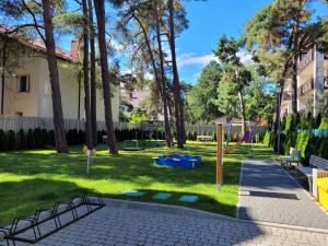 un parc arboré et une aire de jeux avec bancs dans l'établissement Rezydencja Park Mielno Lake View, à Mielno