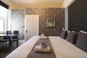 Un dormitorio con una gran cama blanca y una mesa en The Snowdonia Apartments, en Llandudno