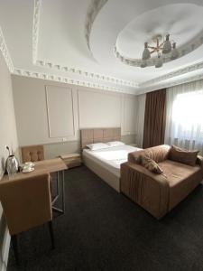 タラズにあるSapphire hotelsのベッドルーム1室(ベッド1台、ソファ、テーブル付)