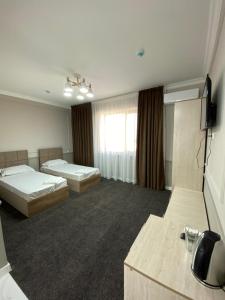 a hotel room with two beds and a television at Sapphire hotels in Taraz