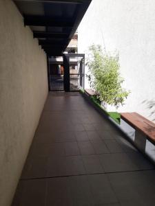 a walkway with a bench and a tree in a building at París 1 Monoambiente in Rosario