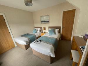 um quarto de hotel com duas camas e uma porta em The Paddock Guest House em Keswick