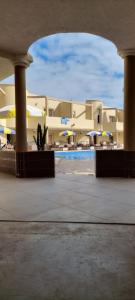 - une vue sur un bâtiment avec une piscine et des parasols dans l'établissement Hotel Beach Club la Perle, à El Jadida