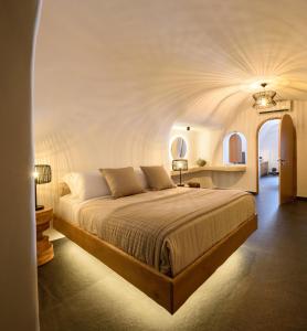 a bedroom with a large bed with a white ceiling at Lotus Cave Villa in Fira