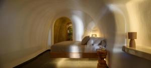 ein Schlafzimmer mit einem Bett in einem Zimmer mit einem Torbogen in der Unterkunft Lotus Cave Villa in Fira