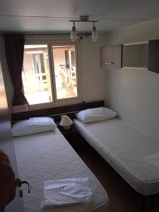 two beds in a room with a window at Mobile home Comfort Ameglia - Including airco - Camping River- 326- 6 pers in Ameglia