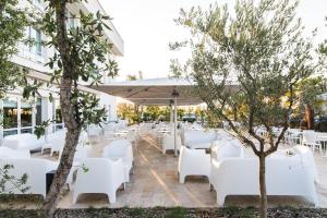 un restaurante con mesas blancas, sillas blancas y árboles en Westotel Tours Val de Loire en La Ville-aux-Dames