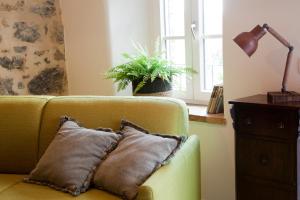 un divano con cuscino, lampada e pianta di Agriturismo La Via Dell'Oliviera a Ciciano