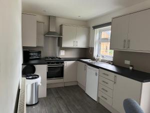 cocina con armarios blancos y encimera negra en Cosy Apartment in Wetheral,Cumbria en Wetheral