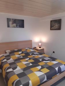 1 dormitorio con edredón negro y amarillo en una cama en Gîte des Marais, en Vaux-sur-Sûre