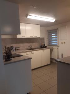 a kitchen with white cabinets and white appliances at Gîte des Marais in Vaux-sur-Sûre